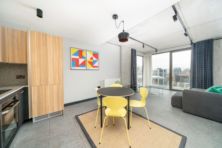 Open plan kitchen and dining area with yellow chairs and large windows