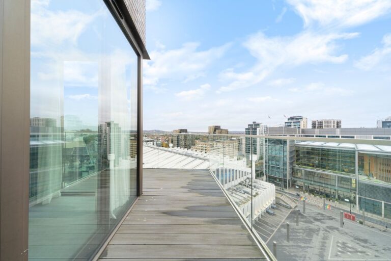 Balcony with glass railing looking out over Wembley Park buildings and streets