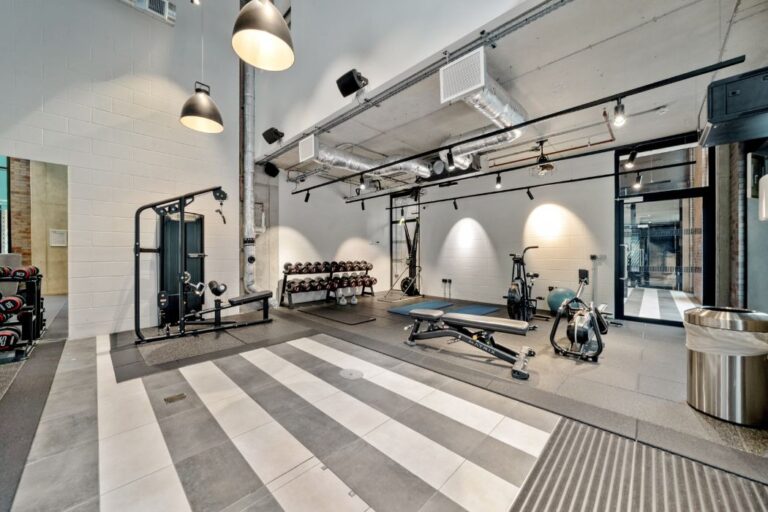 Gym with free weights, benches, and cardio equipment in an industrial style space