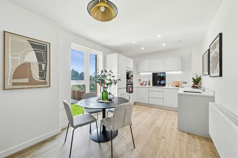 Contemporary kitchen with integrated appliances and dining table by window