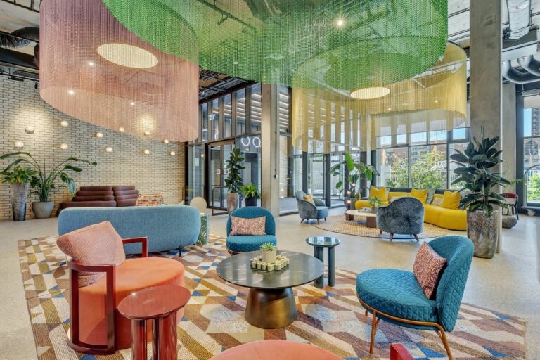 Double-height lobby at 50-60 Charter Street, furnished by Angel O'Donnell with colourful seating areas and decorative chain ceiling installations